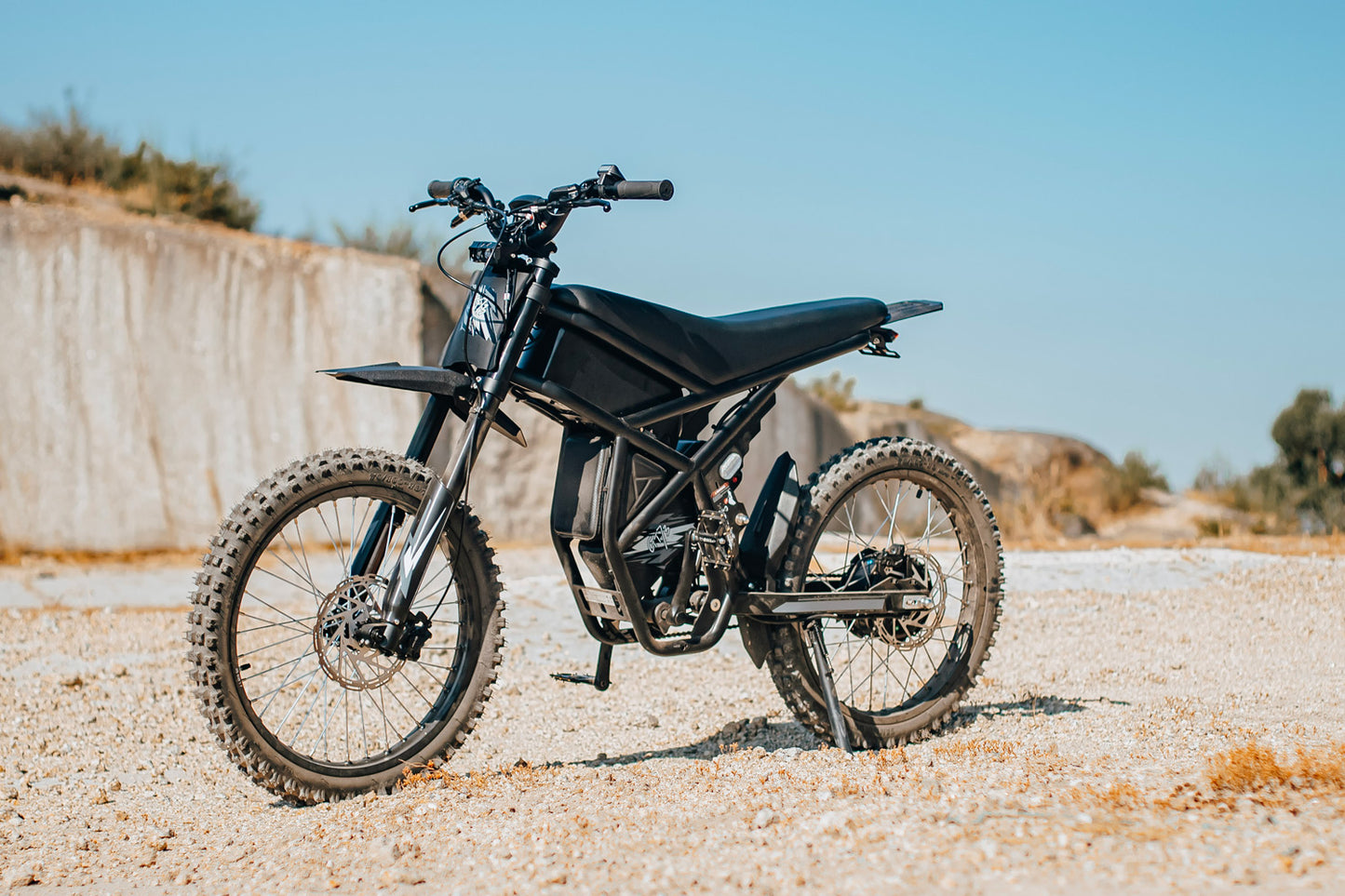 Black electric bike GT73 on a gravel surface with a clear blue sky