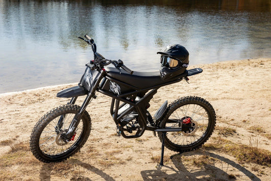 Profile view of the GT73 Electric Dirt Bike with a motocross helmet on the seat, showcasing the dual-suspension system and rugged 25-inch tires.