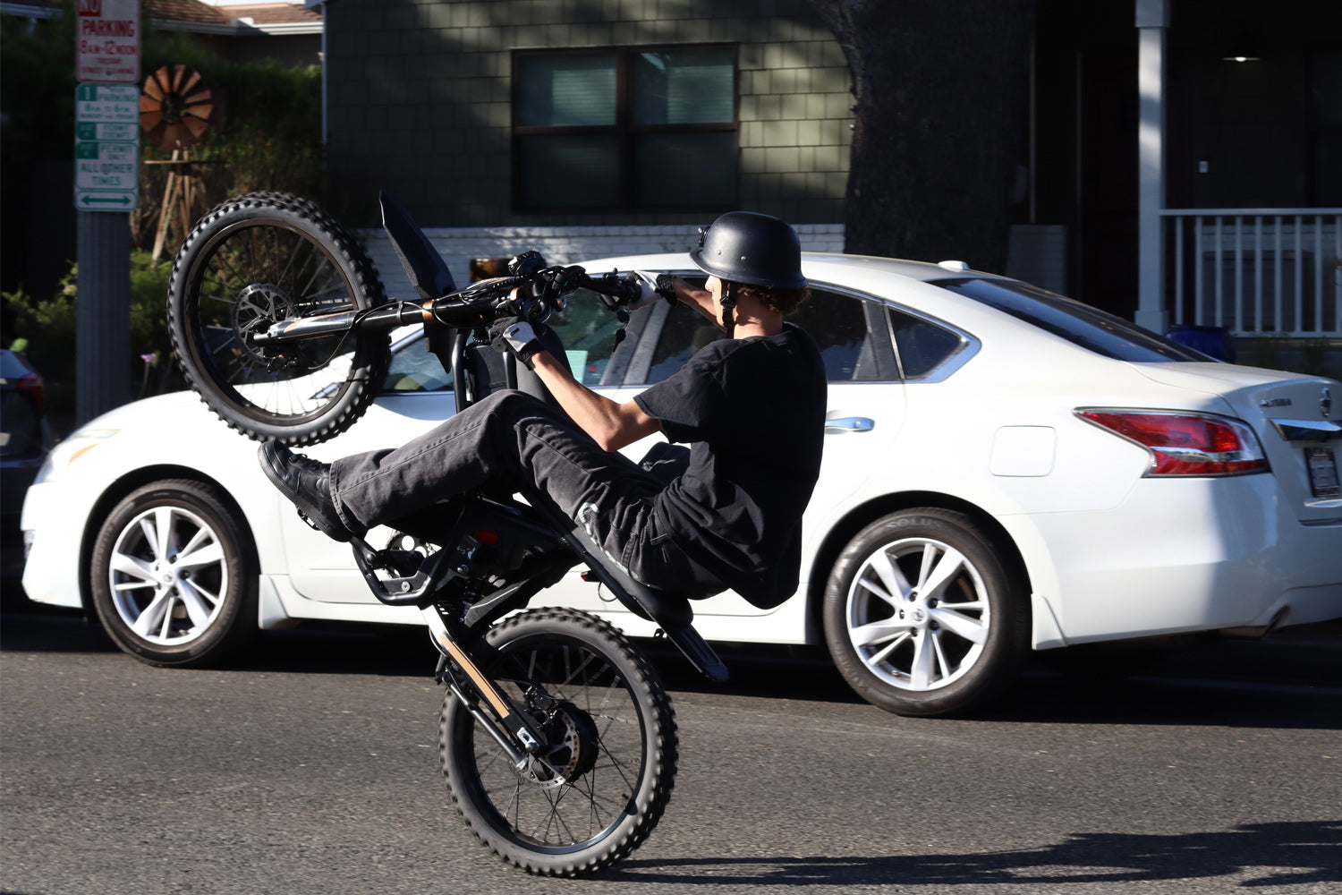 Person performing a wheelie on a GT73Pro Ebike in front of a white car