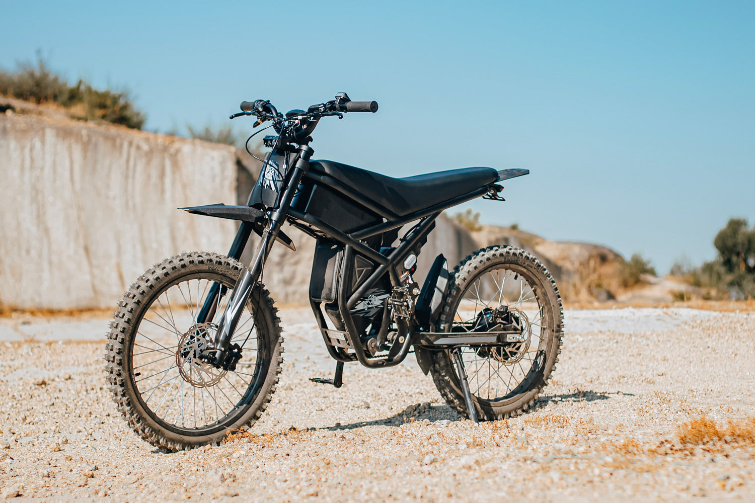 Black electric bike GT73 on a gravel surface with a clear blue sky