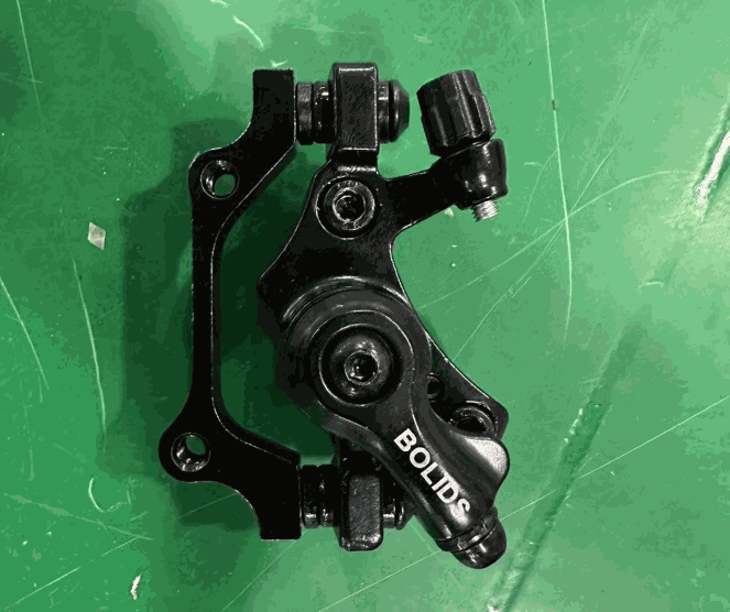 Disc Brake aluminum black mounted component with BOLIDS branding visible on the part against a green background
