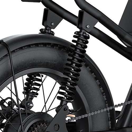 Rear Shock coil spring suspension in black metal on a black off-road bicycle tire with rugged tread pattern