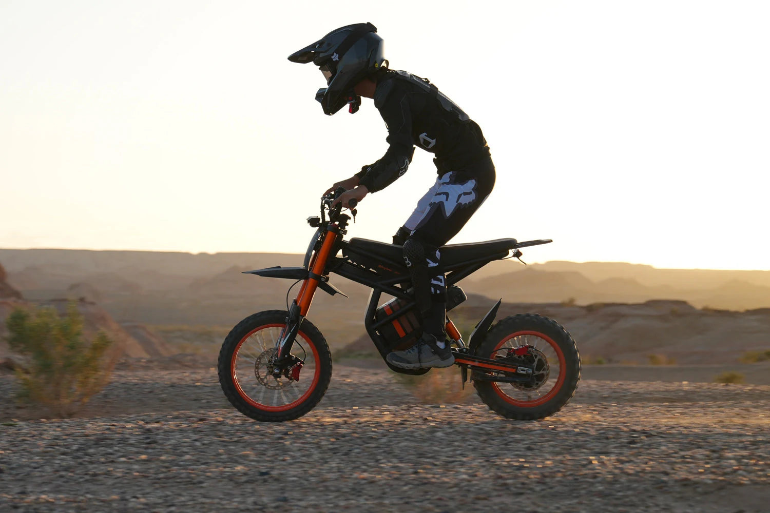 Riding’times GT54 et pilote casqué sur un chemin tout-terrain au coucher du soleil